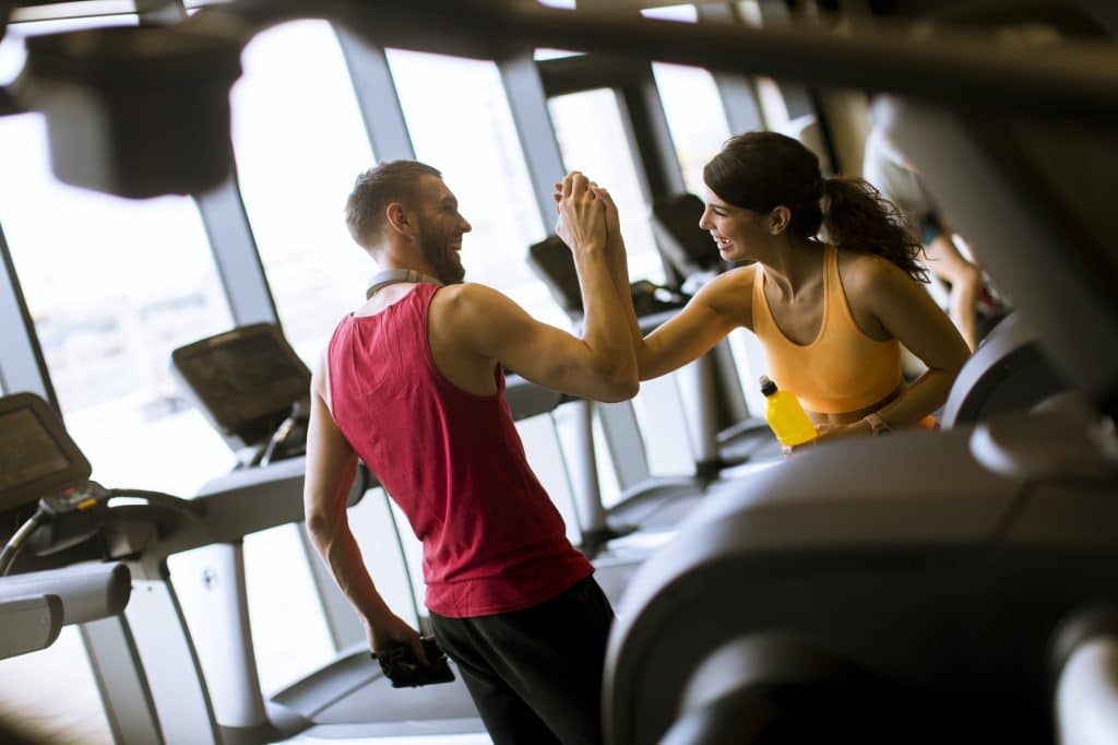 Young woman and personal trainer rest in the gym after workout
