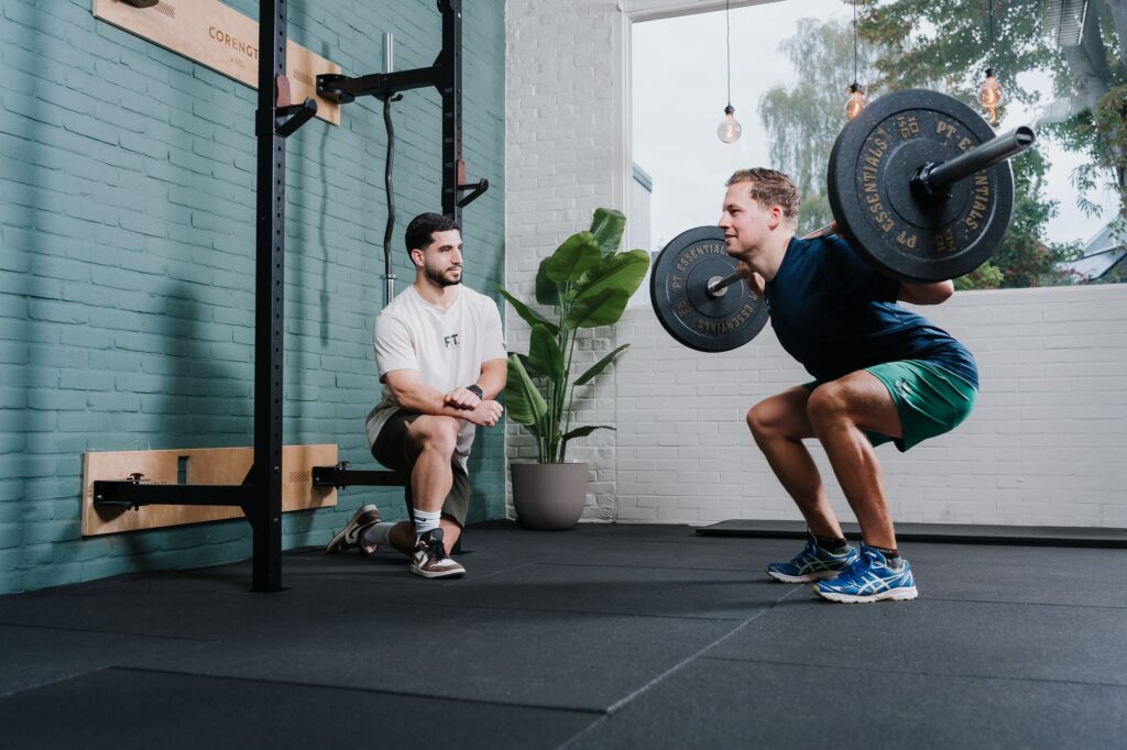 Personal trainer coacht een klant bij de squat
