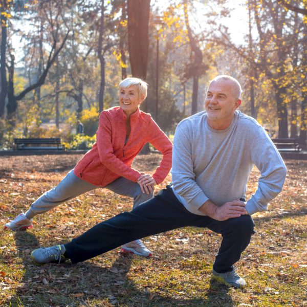A closeup of smiling Caucasian senior couple exercising in a park on a sunny autumn day